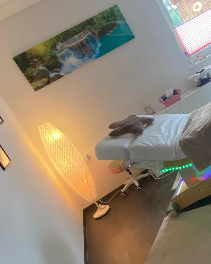 Behandlungsraum von Delfin Massage in Höhnhart: Massageliege mit farbigem Lichtband, Stehlampe und Wandbild